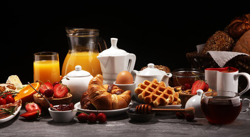 Reichhaltiges Frühstücksbuffet mit Waffeln, Croissants, Säften und frischen Beeren