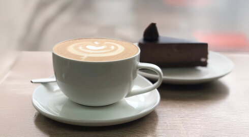 Cappuccino mit Milchschaumherz und ein Stück Schokoladenkuchen
