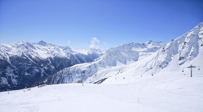 Verschneite Pisten und Berggipfel im Skigebiet Kappl unter blauem Himmel