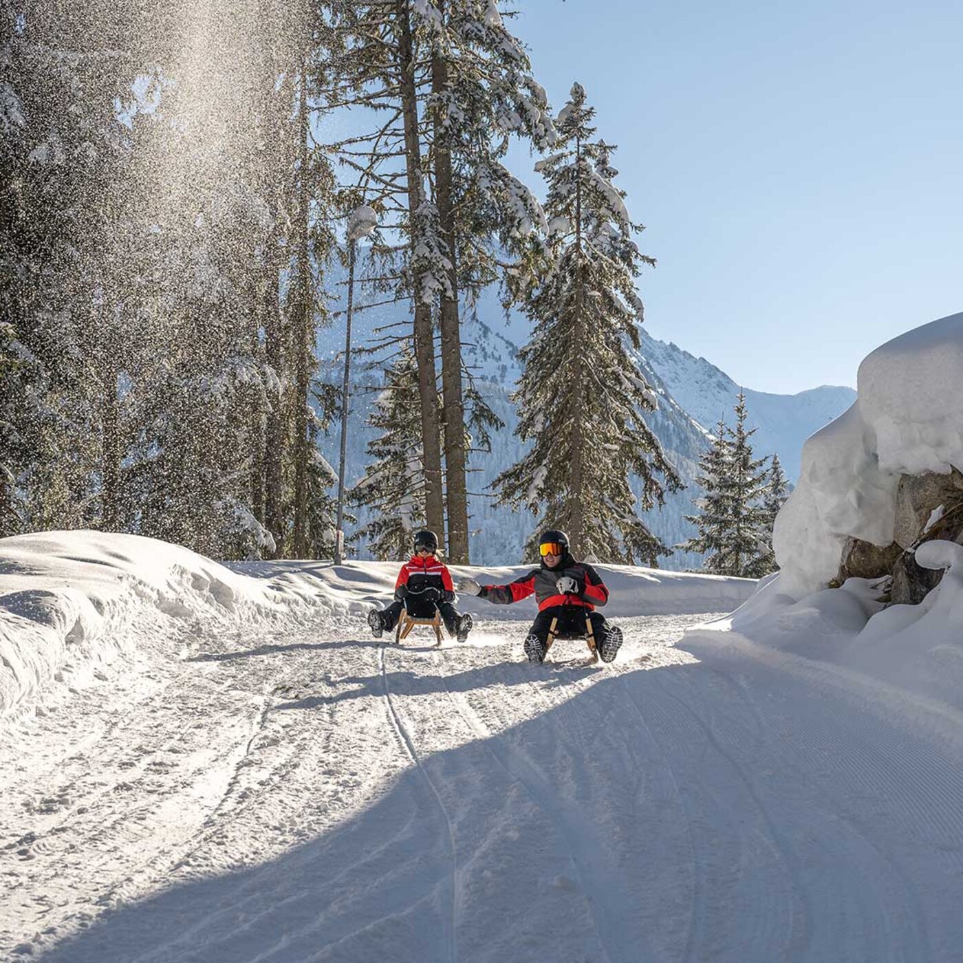 Zwei Rodler auf der Rodelbahn Kappl im tief verschneiten Winterwald