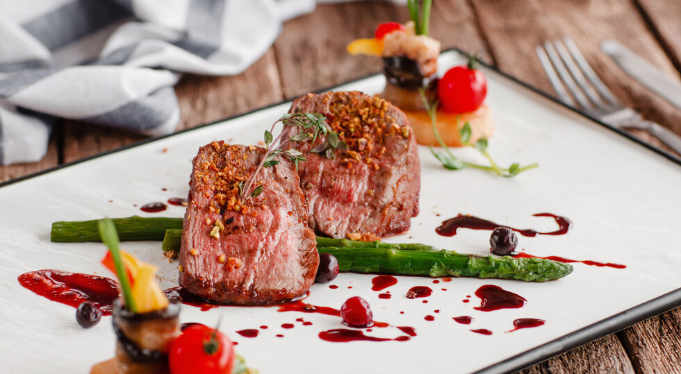 Rosa gebratenes Rindsfilet mit grünem Spargel und Beerensauce, fein angerichtet