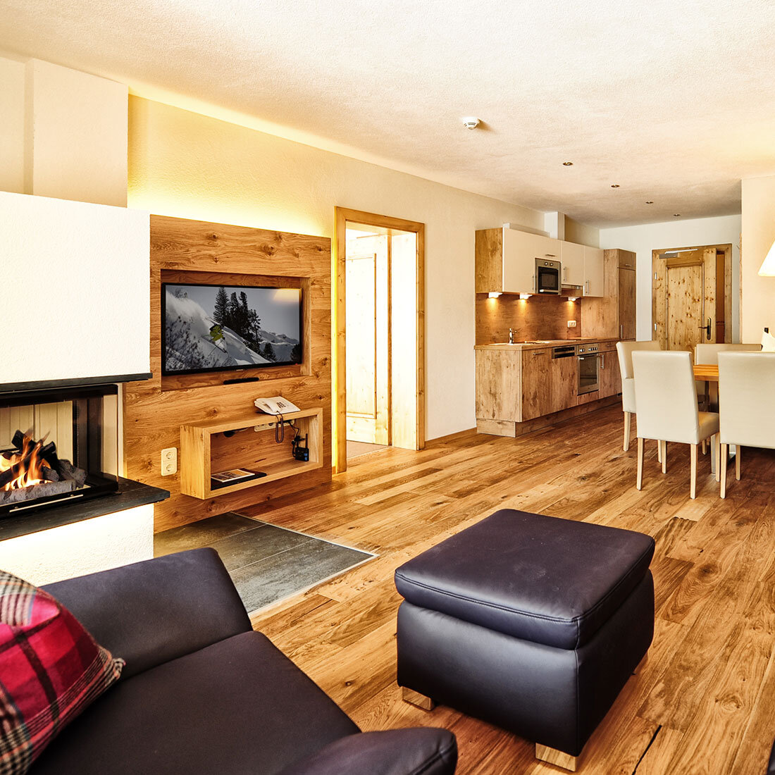 Wohnzimmer mit Ledersofas, Kamin und Essbereich im Alpenstil im Hotel Dorfstadl Kappl