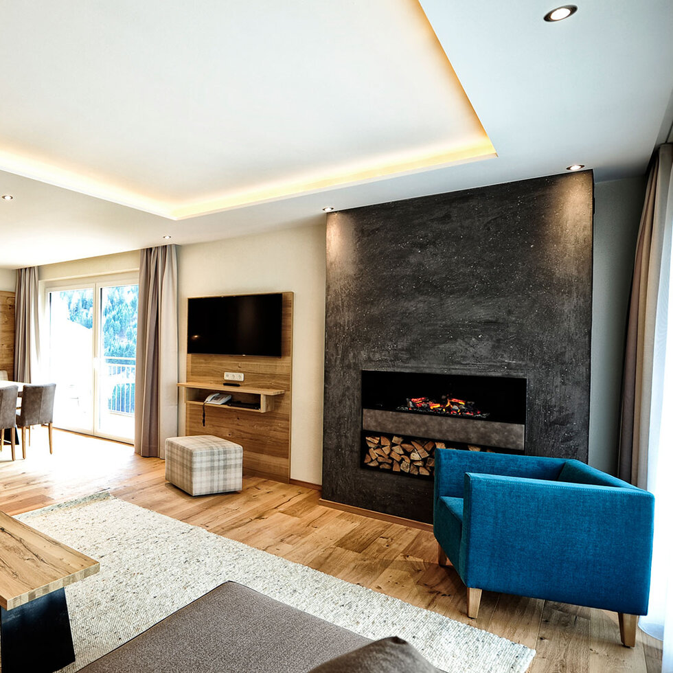 Wohnbereich mit Sofa, Kamin und offener Küche in einem Appartement im Hotel Dorfstadl