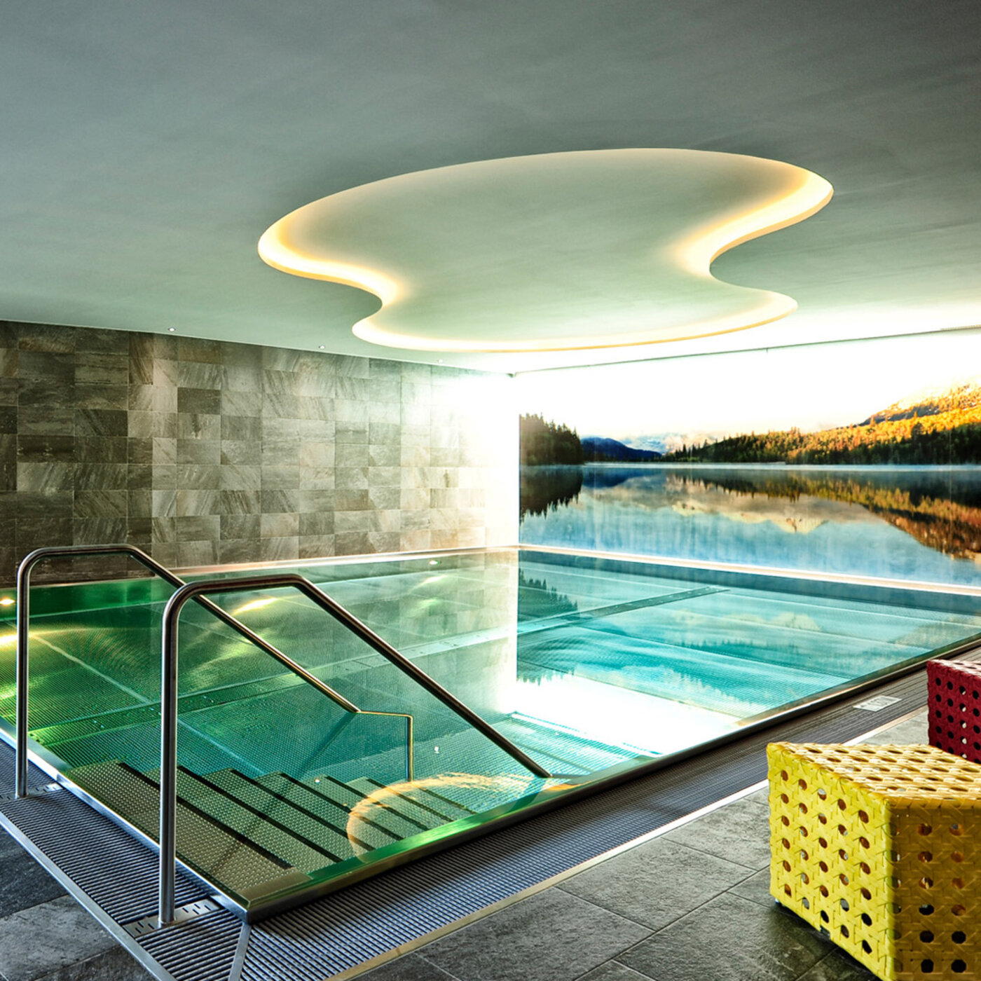 Indoor-Pool mit Natursteinwand und Liegen im Hotel Dorfstadl Kappl