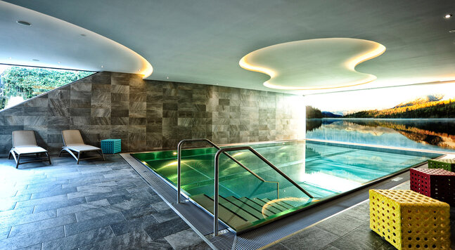 Indoor-Pool mit Natursteinwand und Liegen im Hotel Dorfstadl Kappl
