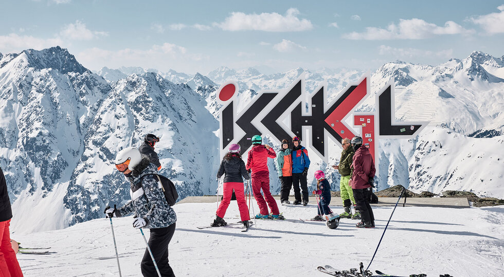 Skifahrergruppe vor dem Ischgl-Schriftzug im Skigebiet