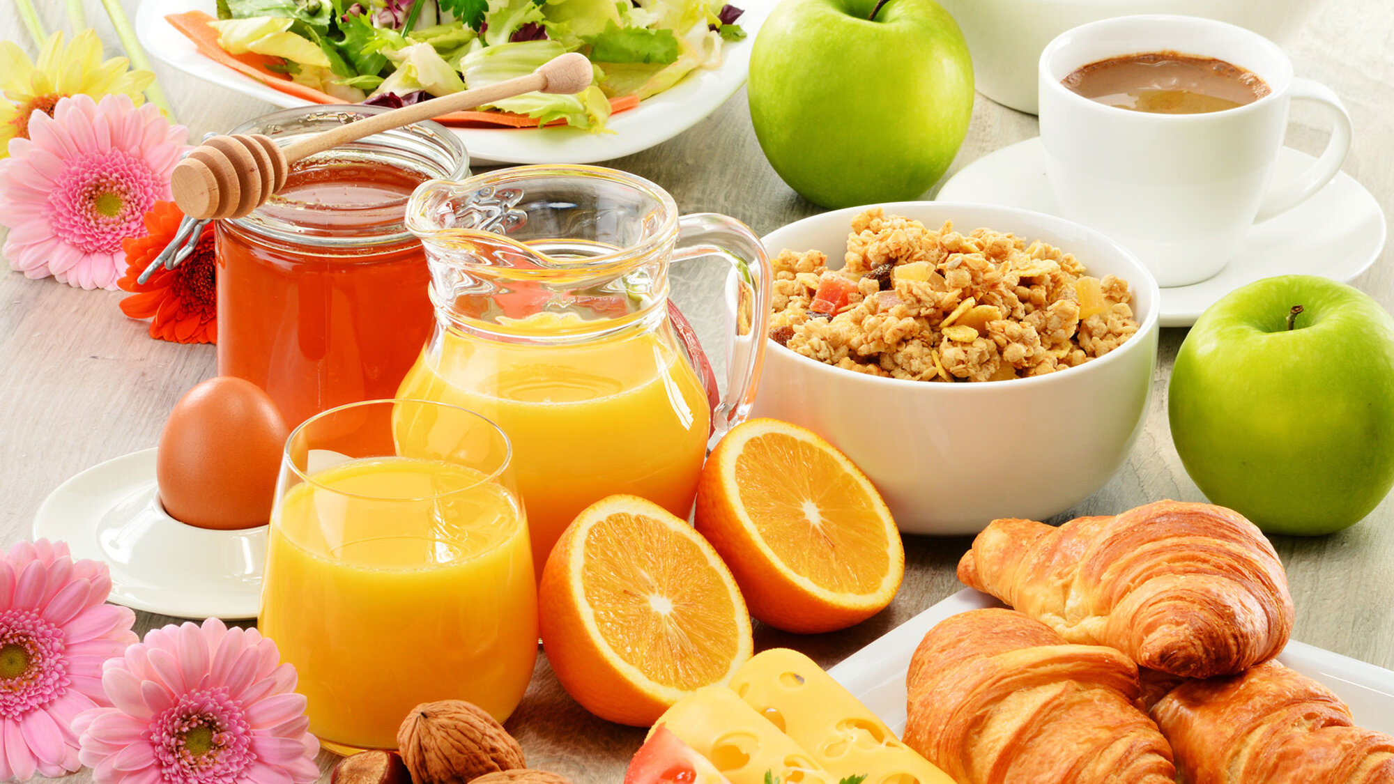 Buntes Frühstück mit Orangensaft, Müsli, Croissants, Obst und Kaffee