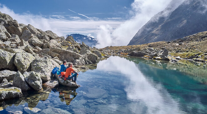 Wanderer rasten an einem klaren Bergsee in der Felslandschaft bei Kappl